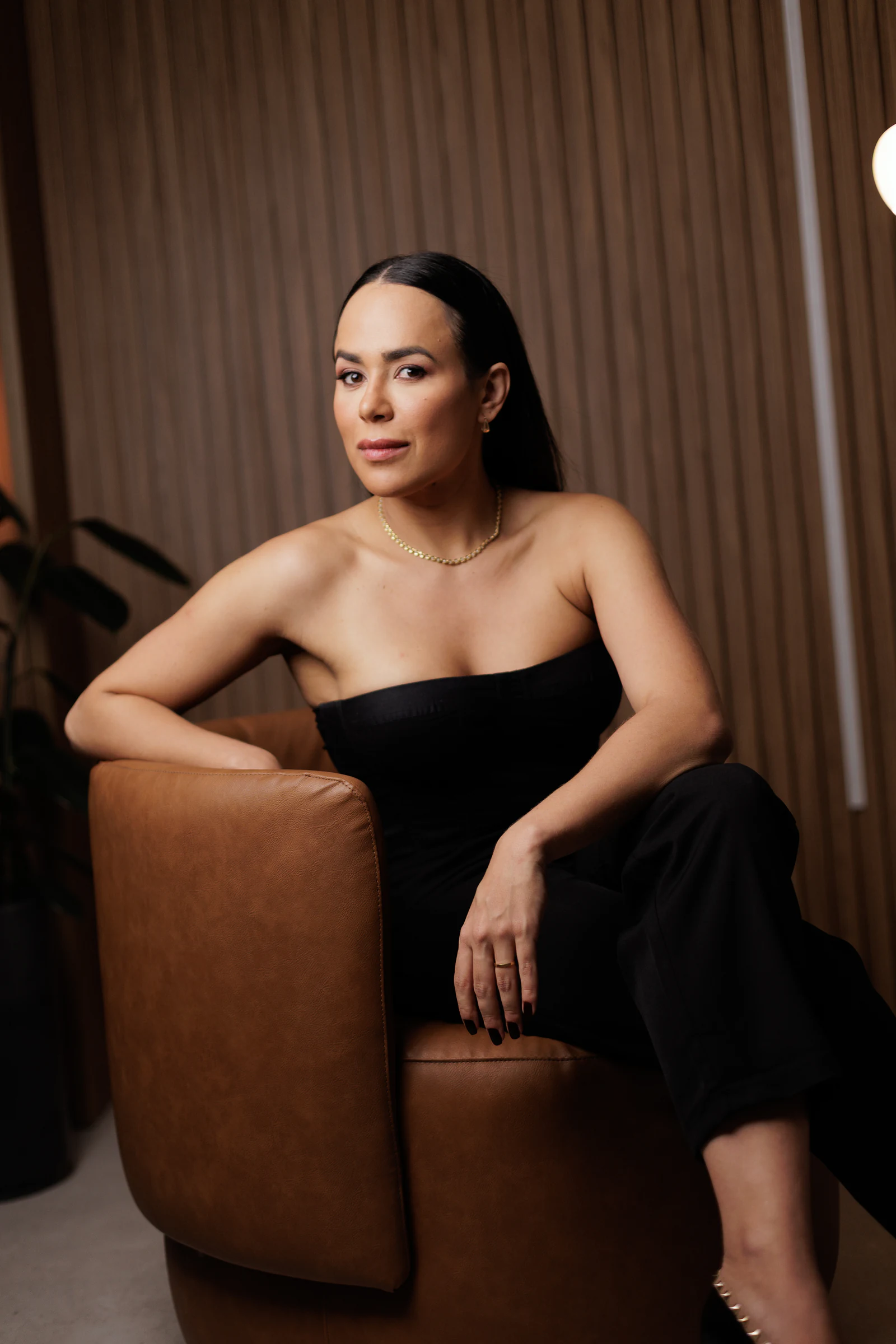 Dra. Paula Fernandes de preto, sentada em poltrona de couro caramelo