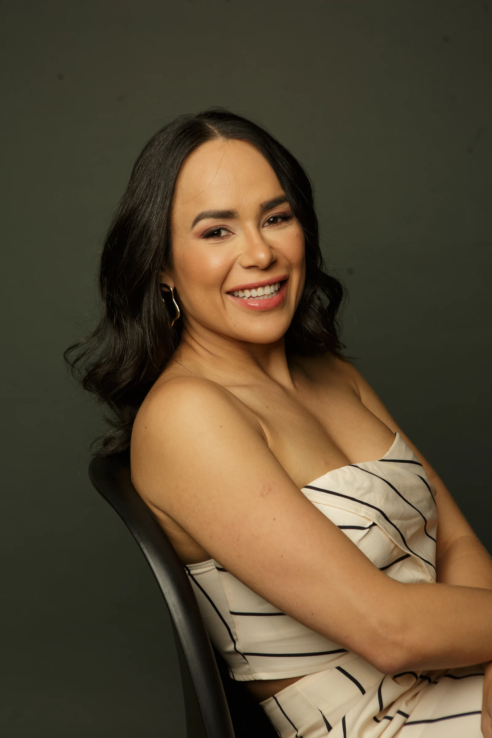 Retrato da Dra. Paula Fernandes sorrindo, sentada, em fundo escuro